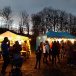 Viele Leute stehen im Freien aus dem weihnachtlich geschmücktem Platz