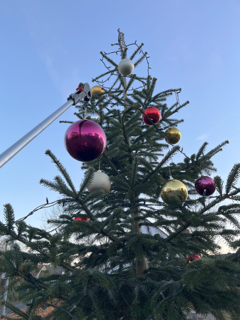Ein Greifarm hält eine Weihnachtsbaumkugel.